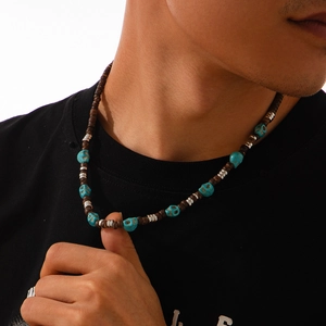 Detail of beaded necklace featuring brown wood beads and turquoise skull charm on model