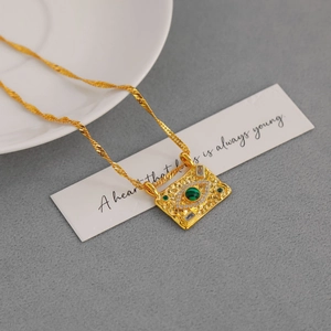 Detail of gold evil eye pendant with green stone and white crystals on twisted chain
