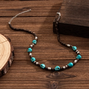Detail of beaded necklace with brown wood beads, blue skull accents and metal extender chain