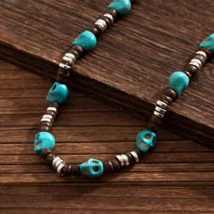 Detail of beaded skull necklace with turquoise stones and wooden beads on wood