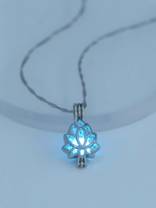 Detailed macro of glowing blue bead inside a hollow lotus pendant on silver chain