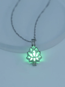 Close-up of luminous hollow lotus pendant necklace glowing green in dark environment