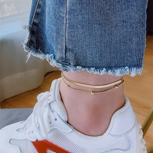 Double-layered gold titanium anklet featuring flat snake chain and delicate gold beads