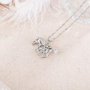 Detailed macro view of a hollow horse pendant with a white bead on a metal rope chain
