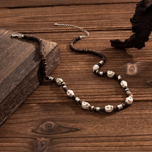 Detailed view of men's punk beaded necklace with skull charms on rustic wooden background