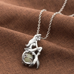 Mermaid pendant necklace with glow-in-the-dark luminous bead on brown woven background