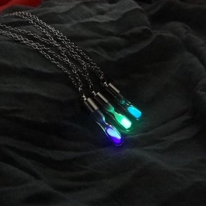 Luminous hourglass crystal pendant necklace set with glowing sand in purple green and cyan