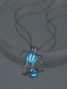 Detailed view of turtle pendant necklace with glowing blue stone in dark lighting