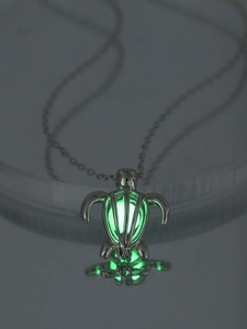 Detailed close-up of turtle-shaped pendant with glowing green light and silver chain