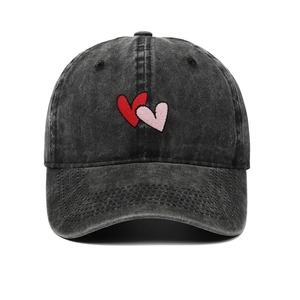 Detail of red heart embroidery on washed cotton vintage style baseball cap in dark grey