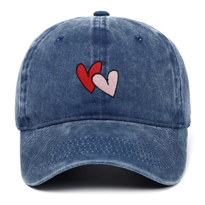 Detailed view of double heart embroidery on vintage washed dark blue denim baseball cap