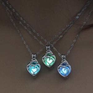 Luminous heart necklaces glowing in blue and green light colors in dark environment