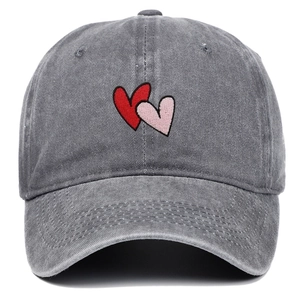 Detailed view of the double heart embroidery on a washed dark grey cotton baseball cap