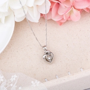 Detailed view of hollow heart pearl cage pendant with silver rope chain on floral background