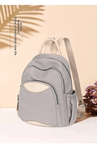 Macro detail of a gray Oxford cloth backpack with multi-layer zippers and side pockets