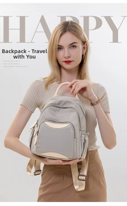 Detailed view of grey oxford fabric backpack with multiple pockets and beige straps