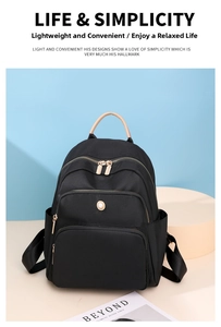 Dettaglio dello zaino in nylon nero con manico in pelle marrone chiaro e tasche con zip