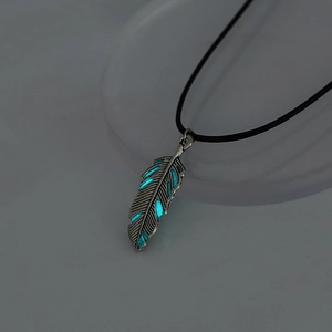 Detailed view of feather pendant necklace with glowing cyan luminous material and silver frame