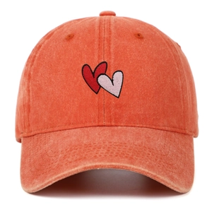 Detail of coral orange washed canvas baseball cap with heart embroidery and vintage texture