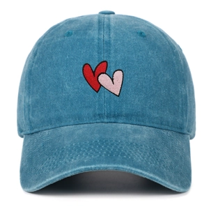 Detail of red and pink heart embroidery on a washed blue cotton baseball cap