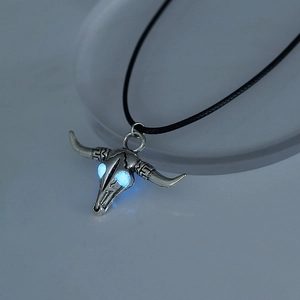 Detailed view of silver ox skull necklace featuring luminous glowing blue eyes at night