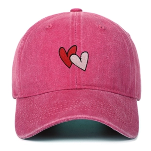 Macro detail of embroidered heart patterns on a washed pink cotton baseball cap