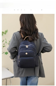 Dettaglio zaino in nylon blu navy con tre scomparti a cerniera e manico marrone