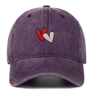 Detail of red and pink heart embroidery on vintage washed purple cotton baseball cap