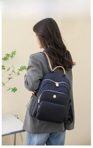 Zaino blu navy con tasche a cerniera multistrato e dettaglio del manico in pelle chiara