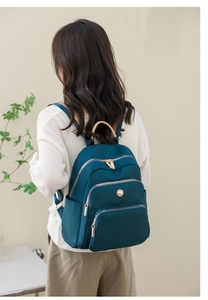 Dettaglio dello zaino verde acqua capiente con tasche multiple e manico color kaki