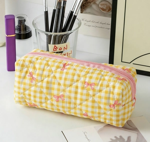 Détail de la trousse de maquillage à carreaux jaunes avec motif nœud rose et matelassage
