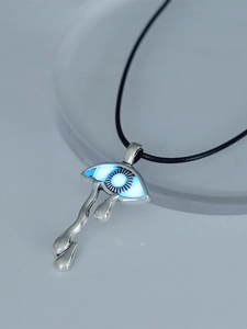 Macro shot of gothic glowing blue eye pendant with silver teardrop detail and cord