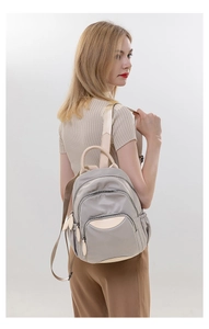 Detailed side view of grey oxford backpack with premium beige leather handles and zippers