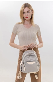 Detail view of light grey oxford fabric backpack with multiple zipper pockets