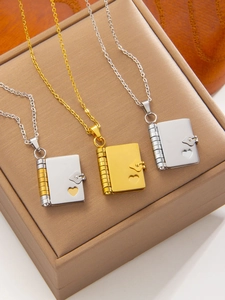 Macro view of book-shaped heart locket necklaces in gold and silver on a jewelry box