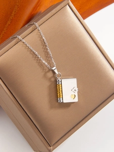 Detailed macro view of book-shaped heart locket pendant in silver and gold tone