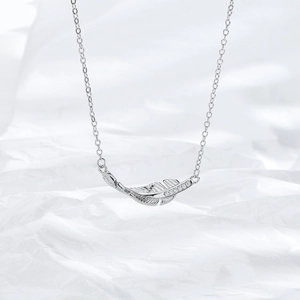 Macro detail of silver feather pendant featuring intricate textures and small sparkling stones