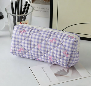 Vue détaillée du sac matelassé à carreaux violets avec motifs nœuds roses et fermeture éclair