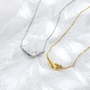Elegant gold and silver feather necklaces with cubic zirconia on white textured paper