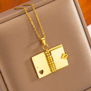 Golden open book pendant necklace with heart cutout displayed on a premium jewelry box