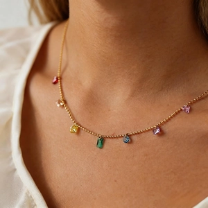 Close-up of golden O-chain necklace with colorful zircon pendants on model