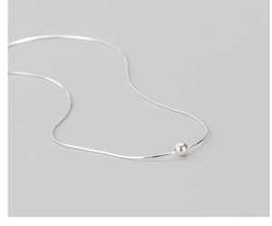 Macro shot of minimalist S925 sterling silver snake chain with polished metal bead pendant