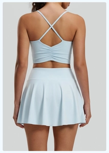 Detalle de conjunto de yoga azul claro con top de espalda cruzada y falda deportiva plisada