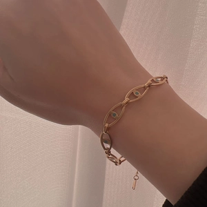 Gold chain bracelet with oval pig nose links and blue enamel details on woman's wrist