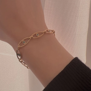 Detailed view of a gold pig nose chain bracelet with blue enamel inlay on a model's wrist