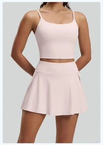 Detalle de conjunto de yoga rosa con top de tirantes y falda deportiva plisada
