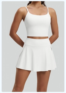 Detalle de conjunto de yoga blanco con top de tirantes finos y falda pantalón plisada
