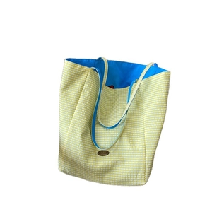 Chic yellow and white checkered canvas tote bag with bold blue straps and brand patch