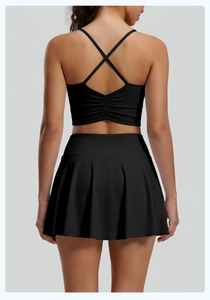 Vista trasera del conjunto de yoga negro con top cruzado y falda de tenis plisada