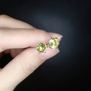 Detailed close-up of six-prong stud earrings with yellow round-cut stones held by hand